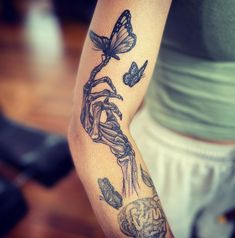 a woman with a tattoo on her arm holding a flower and butterfly in the air