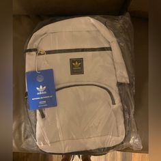 The National 2.0 Backpack From Adidas Originals Comes In A White Colorway With Black And Gold Accents Throughout. The Main Compartment Has A 16" Laptop Sleeve Within And The Smaller Compartment Has Organizers For Loose Items. Adorning The Front Is The Adidas Trefoils Logo On A Black Brand Patch For A Minimalist Look. For Secure Transportation, This Backpack Has A Top Haul Handle And Adjustable, Padded Shoulder Straps. White Backpack With Zipper Closure For Streetwear, White Nylon Backpack For Streetwear, White Nylon Bags For Streetwear, White Bags For Back To School Streetwear, White Bags For Streetwear And Back To School, White Standard Backpack For Streetwear, Black Bookbag, Backpack Adidas, Black And Gold Accents