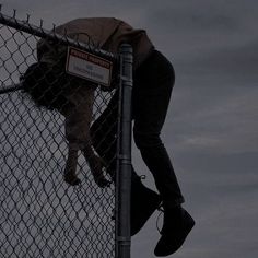 a person climbing up the side of a fence