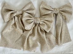 two large bows are sitting on top of a white cloth tablecloth, one is gold and the other is silver