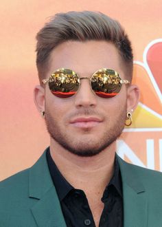 a man wearing gold sunglasses and a green suit