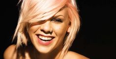 a woman with pink hair smiling at the camera