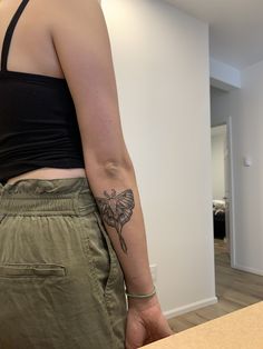 a woman with a butterfly tattoo on her left arm, standing next to a counter