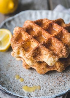 a close up of a waffle on a plate with lemons in the background