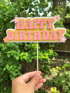 someone holding up a happy birthday cake on a stick