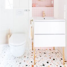 a white toilet sitting next to a sink in a bathroom under a pink wall mounted mirror