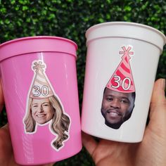 two plastic cups with pictures of people on them, one is pink and the other is white