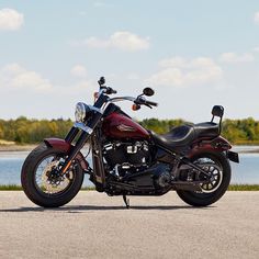 a red and black motorcycle parked on the side of a road next to a body of water