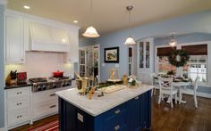 a kitchen with blue and white cabinets, an island in the center is decorated for christmas