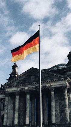 the german flag is flying in front of an old building