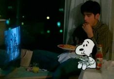 a man sitting in front of a tv holding a plate with a cartoon dog on it