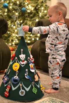 a toddler playing with a christmas tree decorationating it's base in the living room