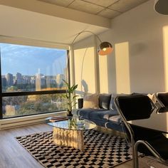 a living room filled with furniture next to a large window overlooking a cityscape