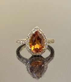 an orange and white diamond ring sitting on top of a table