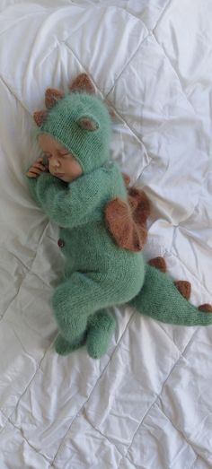 a green stuffed animal laying on top of a bed