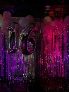 balloons and streamers in the shape of numbers are lit up with purple, pink, and green lights