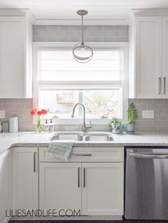 a clean kitchen with white cabinets and stainless steel dishwasher on the countertop