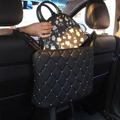 a woman holding a purse in the back seat of a car