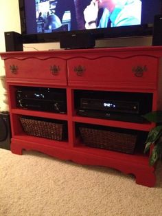 a red entertainment center with wicker baskets in front of it and a flat screen tv on the wall