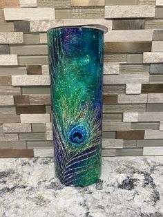 a blue and green vase sitting on top of a counter next to a tile wall