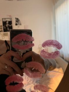 a woman taking a selfie with her phone and pink fake eyelashes on the bed