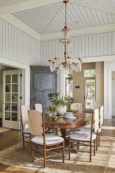 a dining room table with chairs and a chandelier hanging from it's ceiling