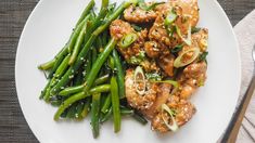 a white plate topped with meat and green beans on top of a table next to a fork