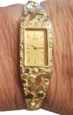 This vintage Seiko wristwatch is a stunning piece of luxury for women. The watch features a polished yellow gold case with a hidden fold clasp closure and a two-piece strap with a maximum wrist size of 6.26-6.75 inches. The cushion-shaped watch face is set with a beautiful gold bezel, and the watch is water-resistant. The watch has a quartz movement and a 12-hour dial, with an unknown number of jewels and year of manufacture. It comes with its original box and packaging, and is a rare find for collectors. The watch has a fixed bezel type and a solid caseback. It is a perfect addition to any dress/formal outfit and is sure to catch the eye of admirers. Bracelet Watches Women Vintage Style, Gold Rectangular Watch With Box Clasp, Gold Rectangular Jewelry For Anniversary, Collectible Gold Watch With Rectangular Dial, Yellow Gold Watches For Anniversary, Formal Engraved Gold Watch, Gold Jewelry And Watches With Polished Finish For Weddings, Gold Polished Finish Jewelry And Watches For Wedding, Wedding Jewelry And Watches In Gold With Polished Finish