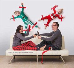 a man and woman are sitting on a couch holding wine glasses while two children jump in the air