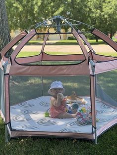 a child's playpen in the grass with a baby doll sitting on it