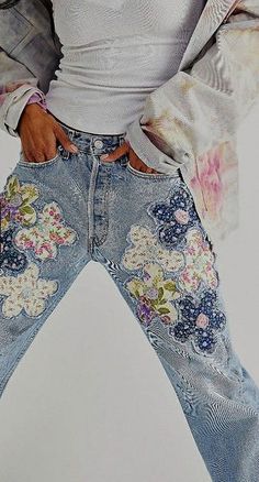 a woman in white shirt and jeans with flowers on her jean pants, posing for the camera