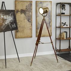 a tripod lamp sitting on top of a wooden stand in front of two maps