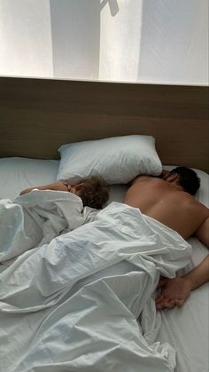 two people sleeping in bed with white sheets