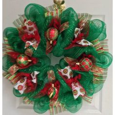 a green wreath with red and gold ornaments hanging on the front door ornament