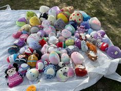 a pile of stuffed animals sitting on top of a white cloth covered table in the grass