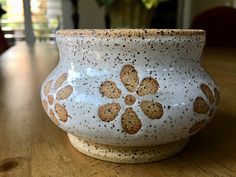 a white vase sitting on top of a wooden table