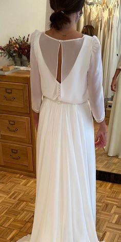 the back of a woman's wedding dress in front of a mirror