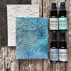 three bottles of ink sitting on top of a wooden table