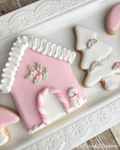 some decorated cookies are on a white platter with pink and white frosted icing