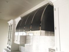 a kitchen with white cabinets and black range hood