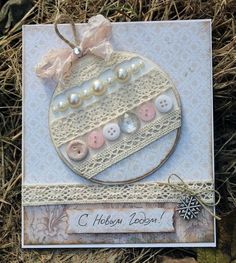 a close up of a card with buttons and lace on the front, in grass