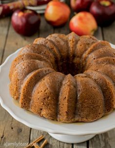 a bundt cake sitting on top of a white plate next to apples and cinnamon sticks