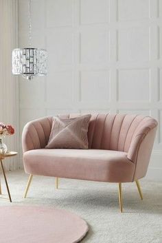 a living room with a pink couch, rug and chandelier hanging from the ceiling