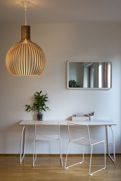 a living room filled with furniture and a mirror on the wall above two white chairs