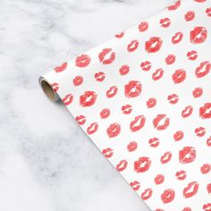 a roll of red lipstick kisses on white wrapping paper next to a marble counter top