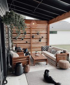 a dog laying on the floor in front of a couch and coffee table under a pergolated roof