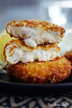 two crab cakes on a plate with lemon wedges