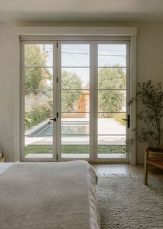 a bedroom with sliding glass doors leading to a pool and patio area in the background