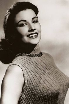 an old black and white photo of a woman wearing a turtle neck sweater with her hands on her hips