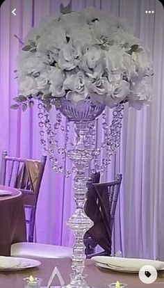 a tall vase with flowers and candles on a table in front of purple drapes